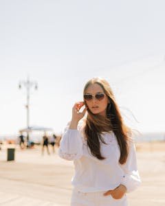 Chic young woman posing in sunglasses on a sunny boardwalk day in New York.